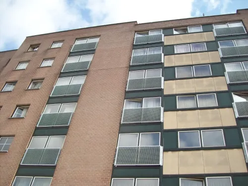 Appartementsgebouw in baksteen met balkons afgewerkt met gegalvaniseerde roosterpanelen