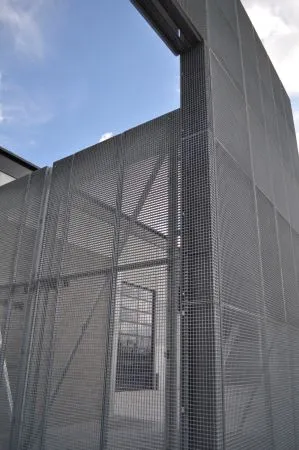 Hoge wand van gegalvaniseerde roosterpanelen tegen een blauwe lucht