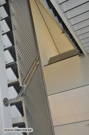 Zicht omhoog in trappenhal met balustrades uit fijne roosterpanelen